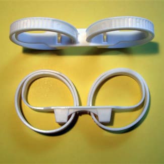 Two pairs of white plastic goggles on a yellow surface.